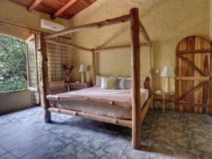 The large master bedroom on the main level has a rustic wood king poster bed and a great jungle view.