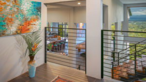 The unique entrance landing looks down over the kitchen and dining area. The original artwork adds a touch of elegance to this deluxe vacation home.