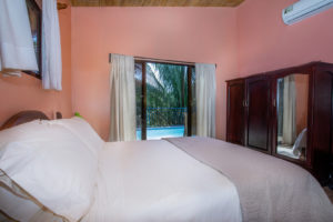 The master bedroom has a large armoire, en-suite bath, and direct access to the pool deck